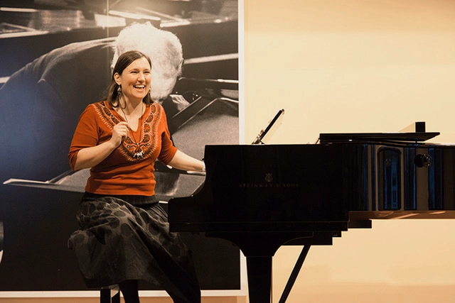 Anna Zackl sitzt lachend und energiegeladen an einem Flügel